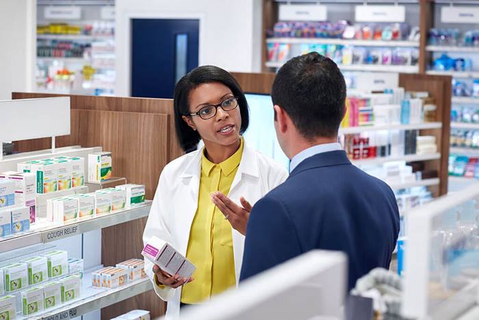 pharmacist and customer cough and cold behind shelf