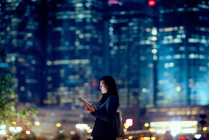 Businesswoman using tablet in urban city at night