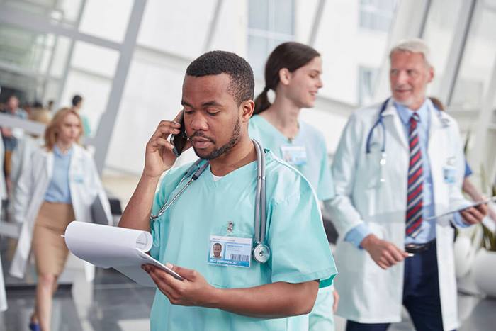 Male nurse with clipboard talking on cell phone
