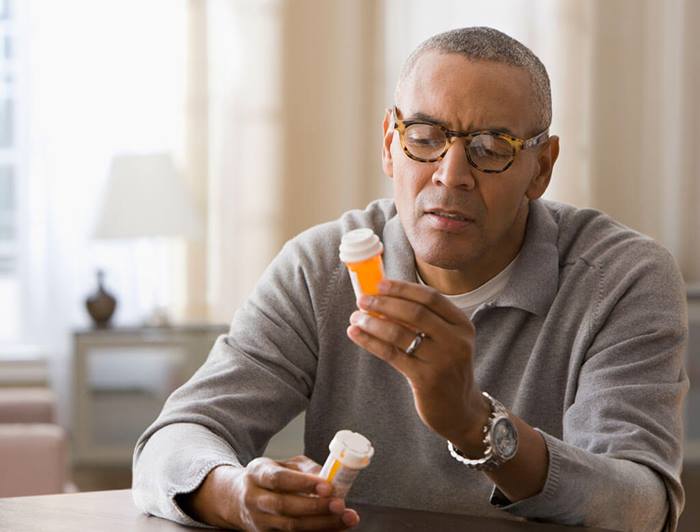 man reading prescription medication bottle