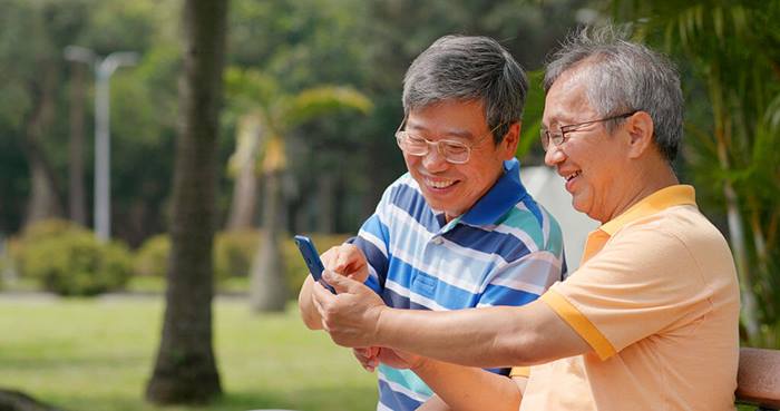 senior males at park with cell phone