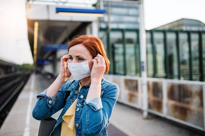 Woman adjusts mask at train station