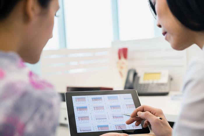 Female medical professionals reviewing charts on tablet