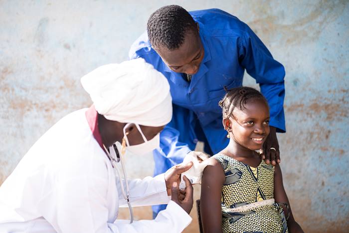 African girl being injected a vaccine dose by a pediatrician