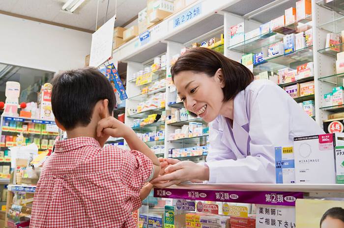 pharmacist looking over at a boy's elbow