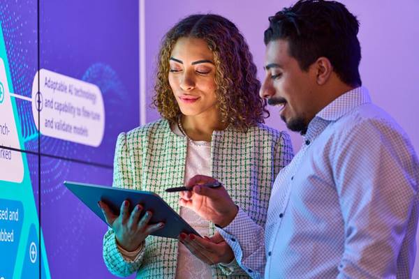 Two professionals reviewing pharma data on screens and tablet, highlighting AI and evolving commercial model insights.