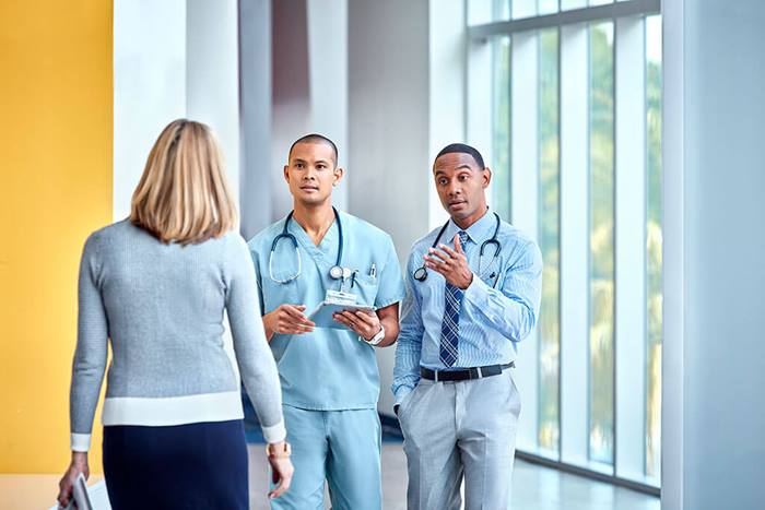 nurse and doctor stopping colleague in hallway