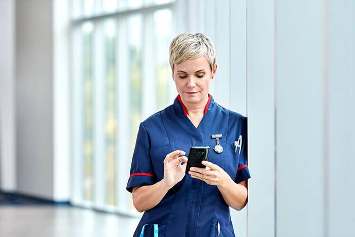 NHS nurse reading information on phone