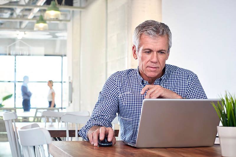 man looking at laptop in cafe