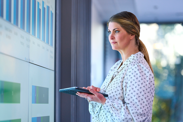 Business woman working with tablet and large screen wall