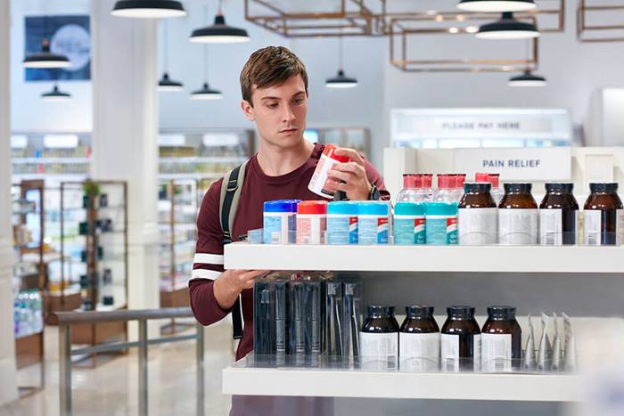 young man pharmacy vitamins jacket off
