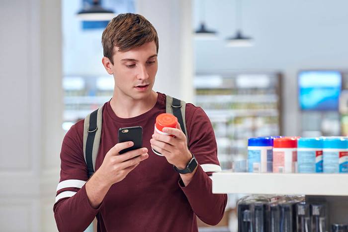 young man scanning bar code pharmacy vitamins jacket off