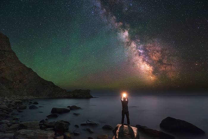 man of black sea shore at night under Milky Way