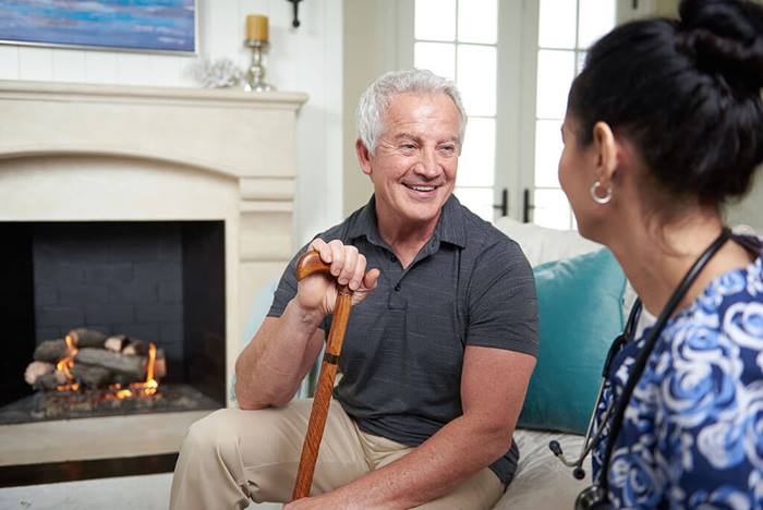 Elderly man with cane chatting with female nurse