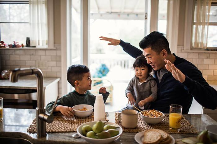 Father and children having breakfast in kitchen